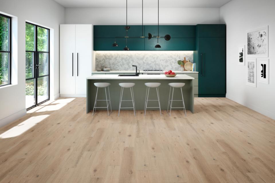 warm toned laminate flooring in kitchen with windows, white counter, and emerald green cabinets.